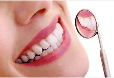 Close-up of a person smiling, showing teeth, with a dental mirror reflecting part of the mouth.